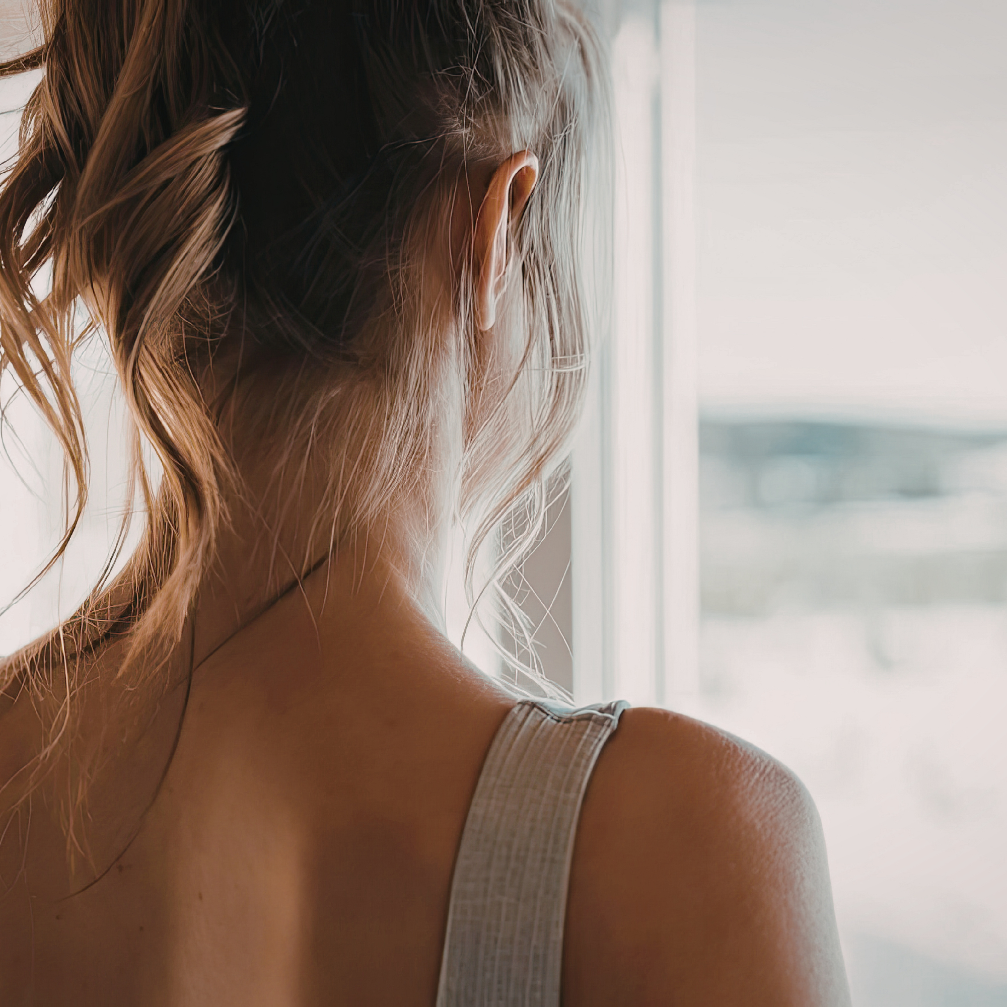 Woman looking out window — Women's Preventive Care